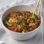Healthy veggie loaded gluten free fried rice in bowl with chopsticks