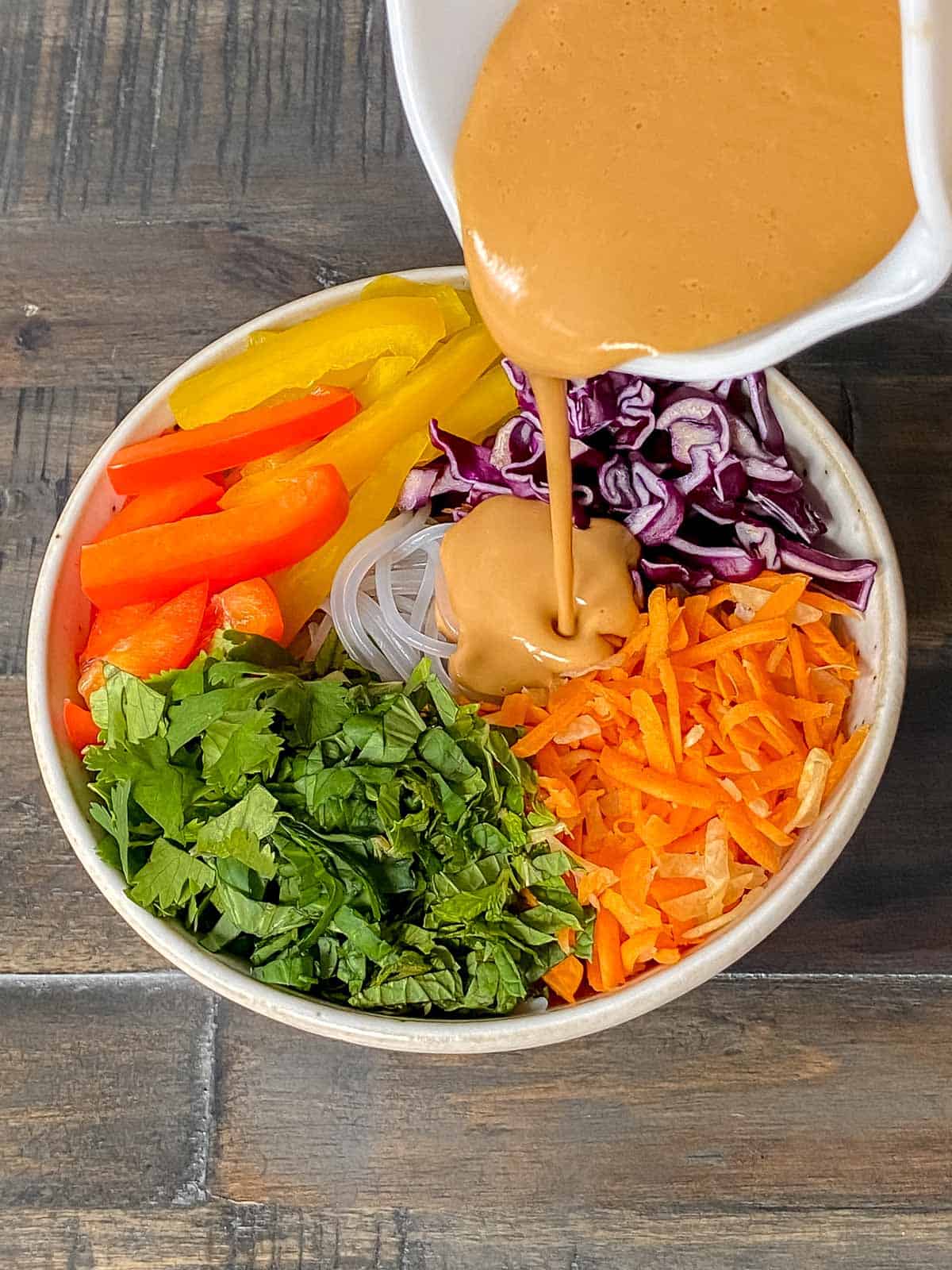 Thai cashew dressing being poured onto Thai noodle salad.