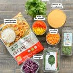 Thai sweet potato glass noodle salad ingedients on table - sweet potato glass noodles, shredded cabbage, cilantro, basil, mint, sliced bell peppers, shredded carrots, cashew or peanut sauce.