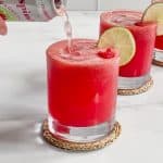lime rickey cocktail in short glass with sparking water being poured into it.