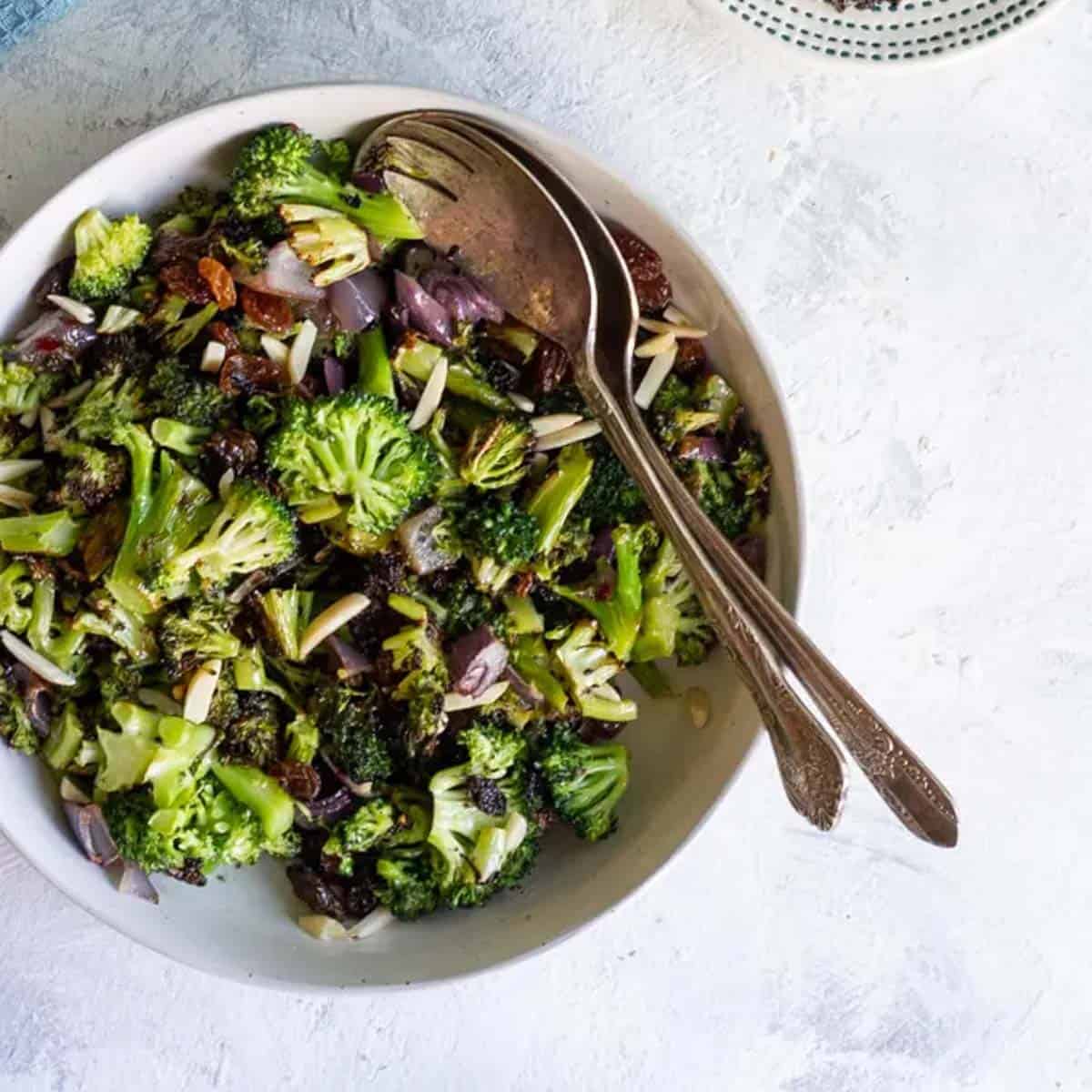 broccoli salad in large bowl with serving spoons.