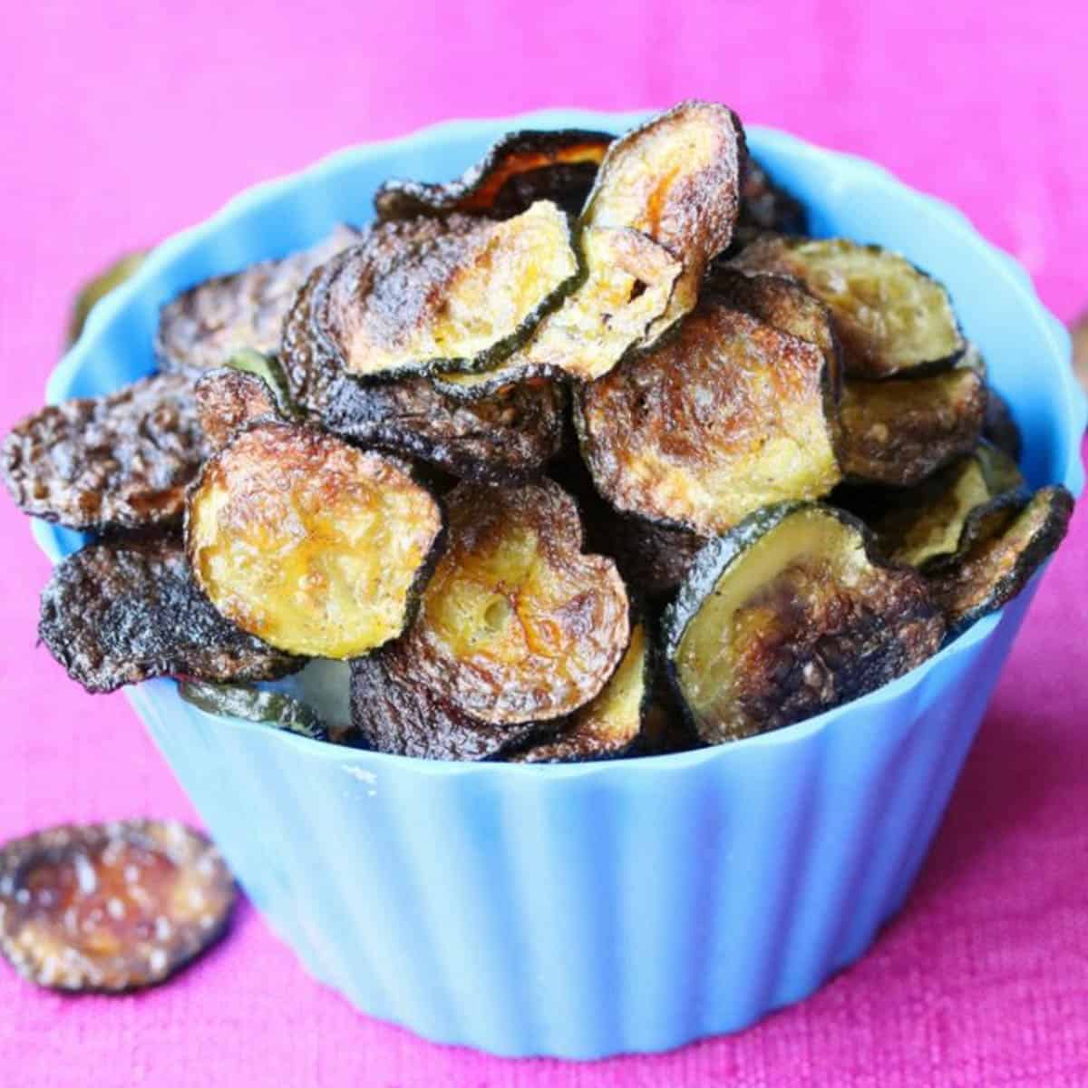 close up of crispy zucchini chips in small blue dish.