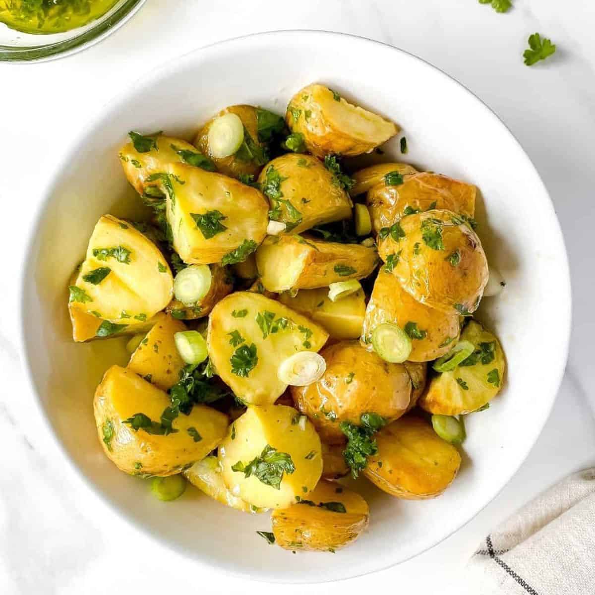 potato salad topped with green onions in white bowl.