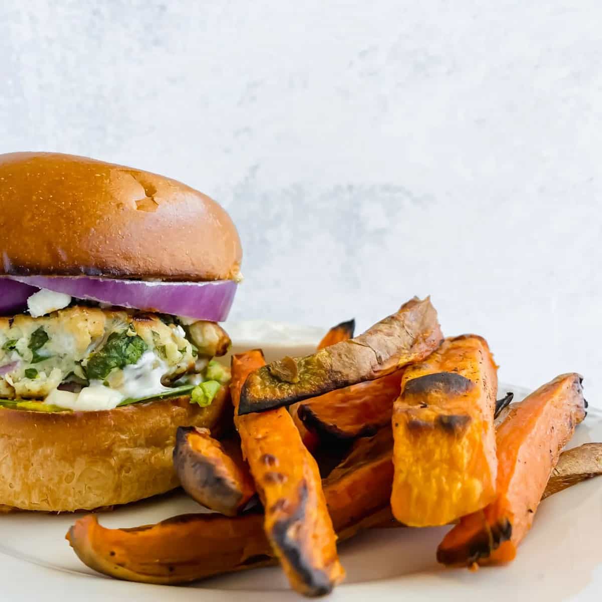 sweet potato fries on a plate next to a turkey burger.