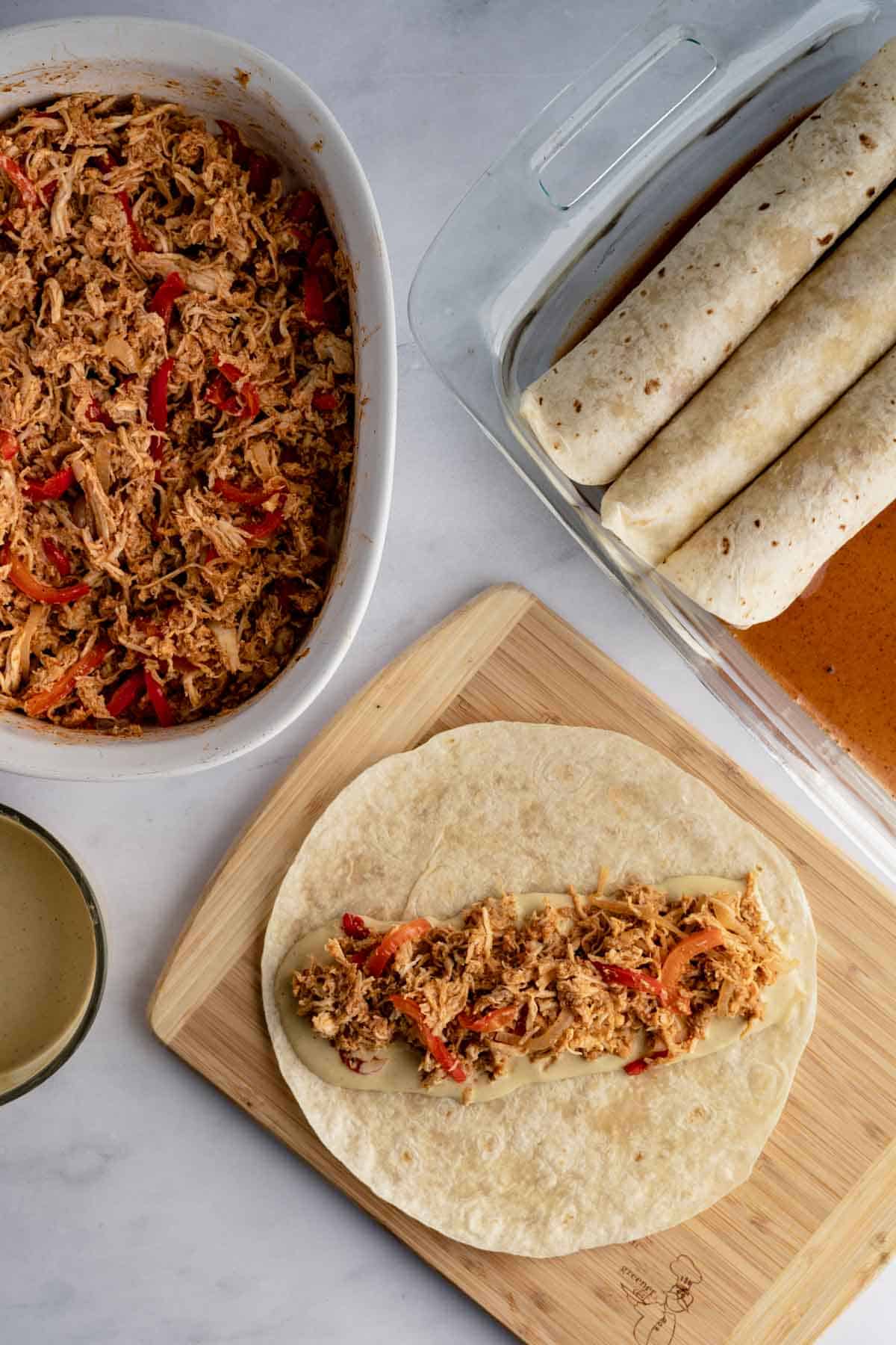 tortilla filled with dairy free cheese sauce and chicken filling before being rolled.
