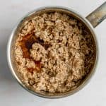 cooked oatmeal in pot with maple syrup on top.