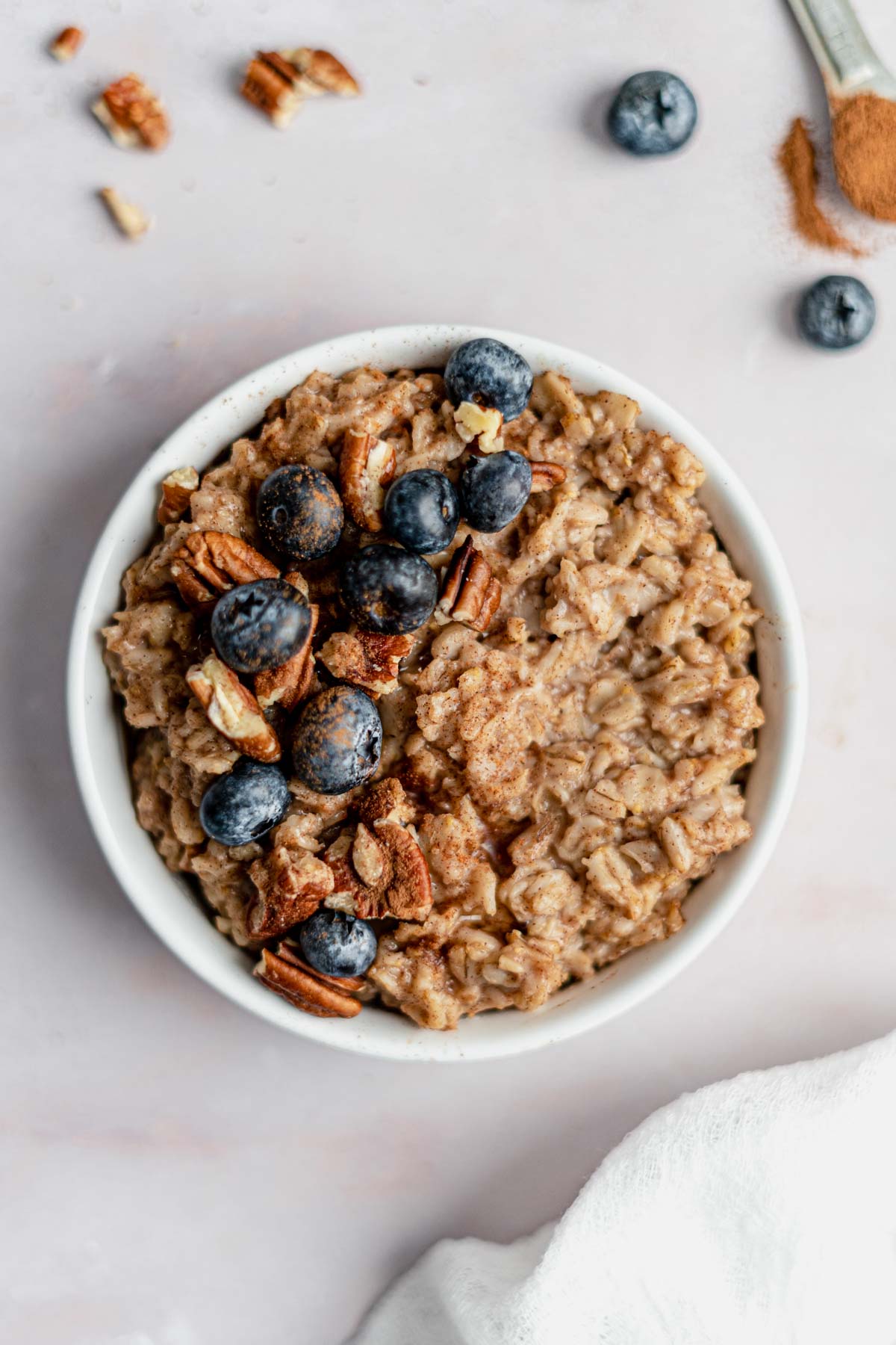 oatmeal in bowl with pecans, blueberries and cinnamon on top.
