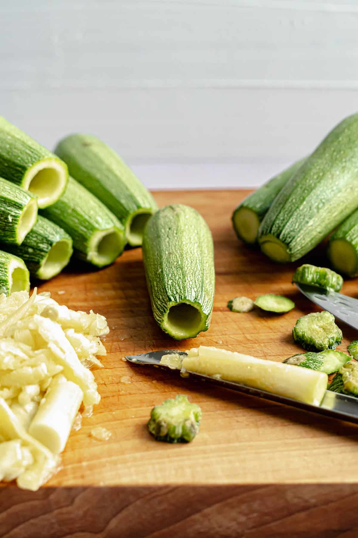 Kousa squash being cored with zucchini corer on cutting board.