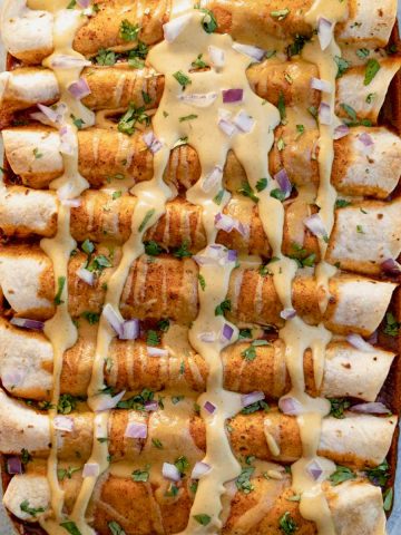 Pan of enchiladas with homemade dairy free cheese sauce on top.