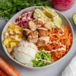 cooked salmon poke bowl assembled in white bowl with spicy mayo drizzled on top.