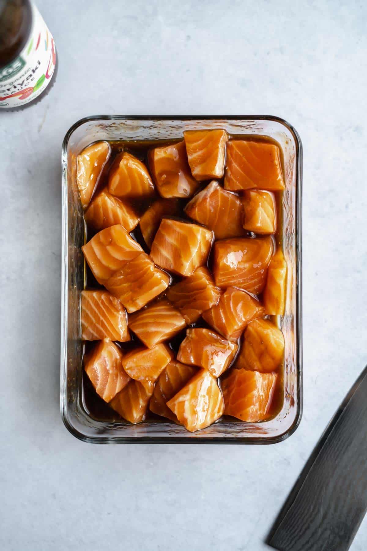 salmon chunks marinating in a bowl of teriyaki sauce.