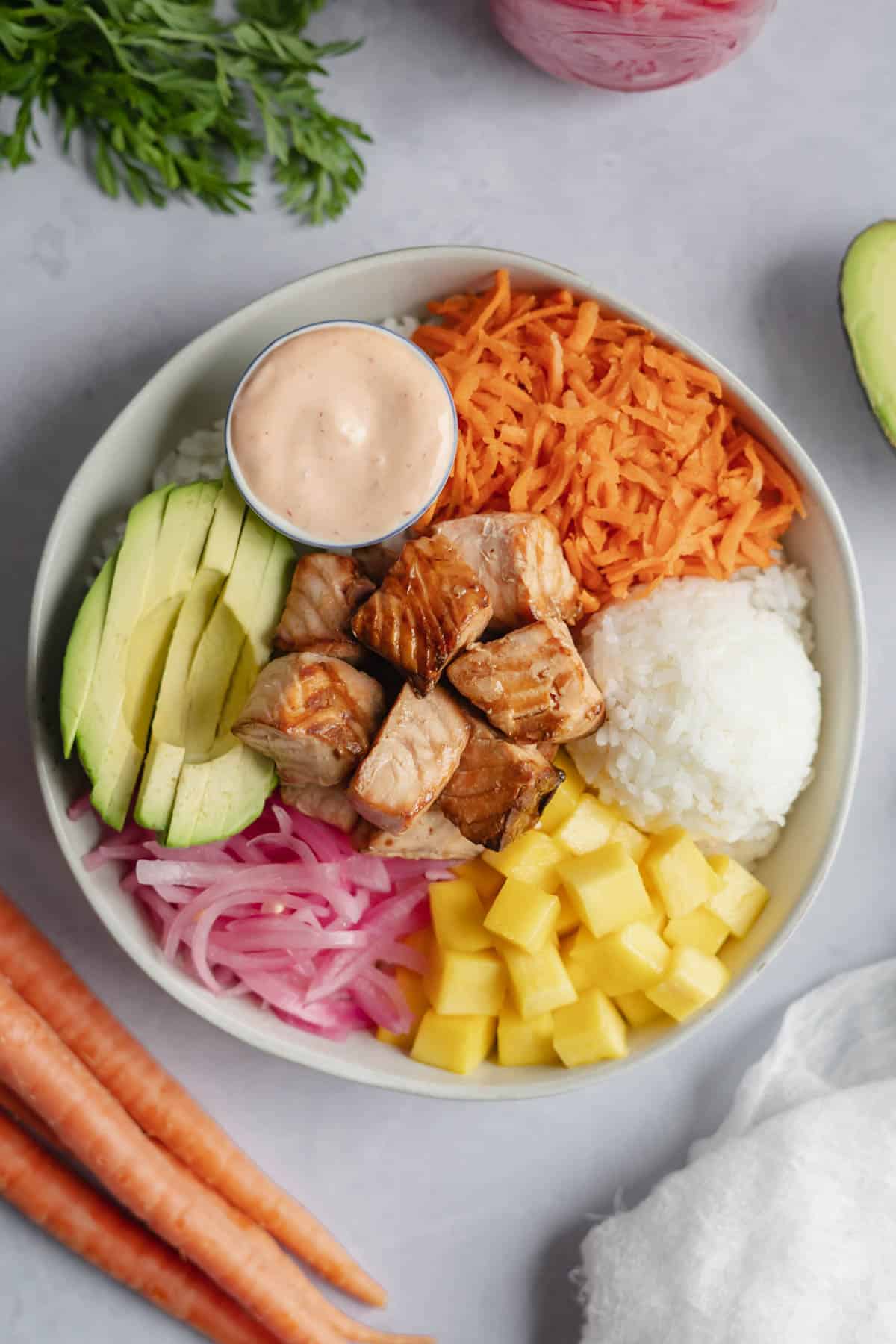 overhead of cooked salmon poke bowl assembled in white bowl.