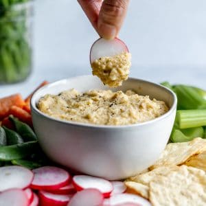 hummus being dipped by a slice of turnip.